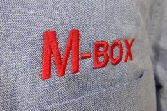オックスフォードシャツの左胸に太めのブロック体で会社名を刺繍した、刺繍屋HONESTの制作事例。糸色は赤単色。