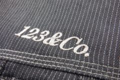 ピッコリ―柄のワークジャケットの左胸にメタリック銀糸でシンプルに社名を刺繍した制作事例。