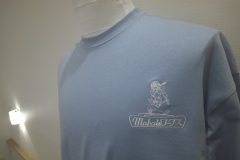 淡いブルーのTシャツの左胸にリフォーム会社のロゴを白糸で刺繍をした制作事例。