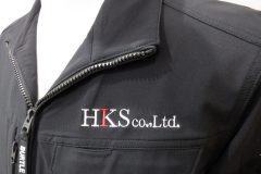 作業服の左胸に白糸と赤糸で会社名をシンプルに加工した制作事例。