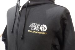 フルジップパーカーの左胸に白糸と金糸で歯科医院10周年のロゴをオリジナル刺繍として製作した、刺繍屋HONESTの加工実績。