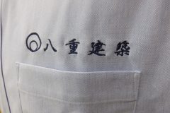 淡いブルーのオックスフォードシャツの左胸にネイビーの糸でシンプルに社名を刺繍した制作事例。