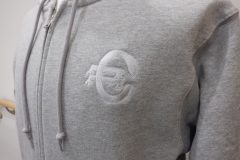 パーカー左胸にスポーツチームのロゴをタタミ縫いをベースに加工した、オリジナル刺繍の制作事例。糸色はホワイト。