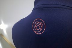 ポロシャツの背中衿下に介護福祉施設のワンポイントロゴをオリジナル刺繍として加工した制作事例のアップ。