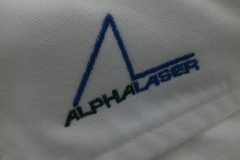 お持ち込みのオックスフォードシャツの襟先部分に企業ロゴを、青と黒の糸でワンポイント刺繍した制作事例のアップ。