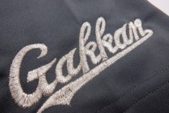 ドライゲームシャツの左袖口に学校のロゴを銀糸で刺繍した制作事例のアップ。サテン縫いによるふっくら感が特徴。