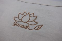 お持ち込みTシャツの背中衿下に蓮の花をモチーフとしたブランドロゴを線画風に刺繍。糸色はライトブラウンを使用。