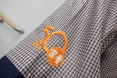 お持ち込みのチュニック左袖口に企業の創業記念ロゴを刺繍した制作事例のアップ。