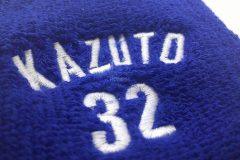 ロイヤルブルーのリストバンドに白糸で個人名と背番号を刺繍した制作事例のアップ。