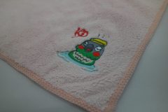 ピンク色のタオルに鳥が温泉に浸かっている様子をモチーフにした刺繍の制作事例。