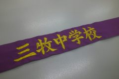 紫のハチマキの中央にメタリック金糸で中学校名を楷書体で刺繍した制作事例。