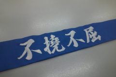 青のハチマキに白糸で「不撓不屈」と刺繍をした制作事例。