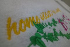 白地のタオルに黄色・緑・ショッキングピンクでオリジナルロゴを刺繡した制作事例のアップ。