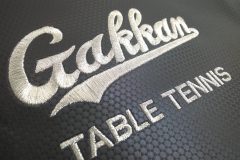 黒のスポーツリュックへ学校のロゴと部活動名を銀糸で刺繡した制作事例のアップ。