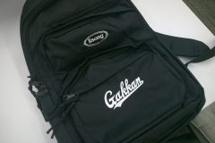 黒のスポーツリュックに白糸で学校のオリジナルロゴを刺繡した制作事例。