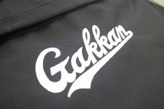 黒のスポーツリュックに白糸で学校のオリジナルロゴを刺繡した制作事例のアップ。
