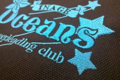 黒のリュックに明るいブルー糸でチームロゴとその下に個人名を刺繍した制作事例のアップ。