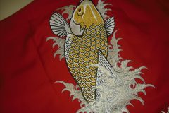 赤い布地の上に金と銀の糸と黒糸で立体的に刺繍された鯉のデザインを刺繡した制作事例。和風の迫力と華やかさが際立つ刺繍。