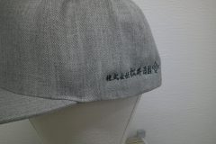 帽子の左サイドに黒糸でシンプルな社名刺繍を加工した制作実績。