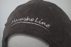 茶色のコーデュロイキャップの背面に筆記体で会社名を刺繍した制作事例。使用糸は銀糸。