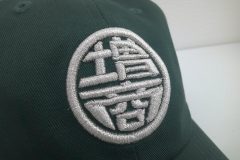 グリーンのツイルキャップフロントに銀糸で社名ロゴをオリジナル3D刺繍として製作した作品実績。