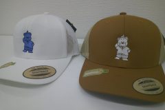二色の帽子のフロントに可愛いクマのキャラクターをタタミ縫いをベースにオリジナル刺繍加工した制作事例。