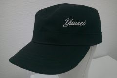 黒のワークキャップフロント（左寄り）にライトベージュでシンプルに会社名をネーム刺繍した制作事例。