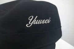 黒のワークキャップフロント（左寄り）にライトベージュでシンプルに会社名をネーム刺繍した制作事例のアップ。