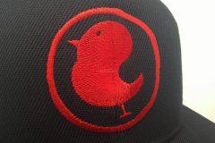 黒のベースボールキャップの前面に赤糸で焼き鳥店のロゴをオリジナル刺繍として加工した、制作事例のアップ。