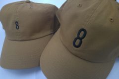 キャメルカラーの帽子のフロントに大きめのサイズで8と数字をサテン縫いで加工した帽子刺繍の制作事例を二つ並べたもの。