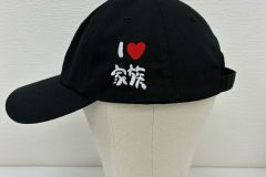 黒のキャップ左サイドに家族向けのメッセージを手書き風のフォントで刺繍した制作実績。