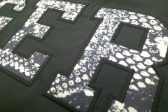 黒いジャケットの背中部分にパイソン柄の生地を黒糸で縁取り刺繡した制作事例のアップ。