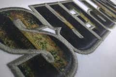 白のTシャツに森林の画像をプリントした生地をベージュ糸で縁取り刺繡した制作事例のアップ。
