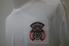 白いTシャツの左胸に防士を象徴するイラストがプリントされた生地を縁取り刺繡した制作見本。