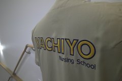ベージュのスクラブの背中に医院名を縁取り刺繍した制作事例のアップ。ベース生地にはサテン地を使用。刺繍糸は濃紺。