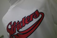 ヒゲ付きタイプのスポーティーな筆記体ロゴを白のTシャツのフロント縁取り刺繍した制作事例のアップ。千葉の刺繍屋HONESTの作品。