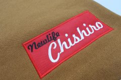 ワークエプロンの左すそに赤のボックスを縁取り刺繍。その上には黒糸と白糸で店名を刺繍した作品。