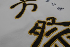 白の濃口シャツの背中に「五方祭」と加工。黒の部分はサテン生地を使用。その生地を金糸で縁取り刺繍した制作事例のアップ。