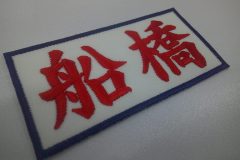 白のツイル生地に赤糸で地域名を大きめ刺繍した、文字ワッペンの制作事例。