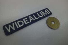 濃紺のエンブクロス生地に白文字で会社名を刺繍した文字ワッペンの制作事例。