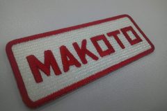 白のエンブクロス生地に、赤糸で刺繍をした個人名の文字ワッペン。