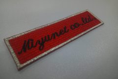 赤のエンブクロスに英字筆記体で会社名を刺繍。文字色は黒。外周フチは銀糸の文字ワッペンを制作した事例。