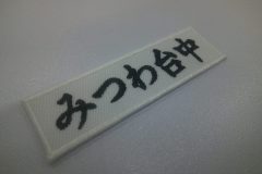白のツイル生地に中学校名を黒糸で刺繍した、文字ワッペンの作品実績。
