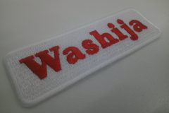 白の生地に発色の良い赤糸でレーシングチーム名を刺繍した文字ワッペン。形状は長方形の角丸。