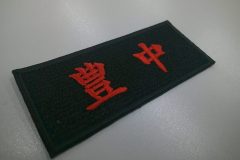 黒の生地に赤糸で地域名を刺繍した、コンパクトなサイズの文字刺繍ワッペンの加工事例。