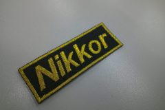 黒生地にメタリック金糸で店名を刺繍した、文字ワッペンの作品事例。オリジナル書体を使用。