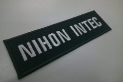 黒のツイル生地に白糸でゴルフ場名を刺繍した、長方形の文字ワッペン。