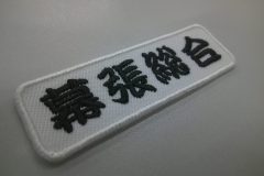 勘亭流書体で学校名を刺繍した文字ワッペン。白生地に黒糸で加工。