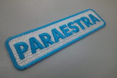 白のエンブクロスにターコイズブルーで道場名を刺繍した、文字ワッペンの制作事例。