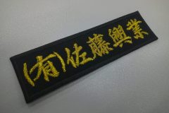 濃紺のエンブクロス生地に金糸で会社名を刺繍した文字ワッペン。書体は行書体を活用。